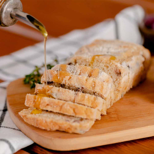 Pao-ciabatta-sabor-azeitonas-pretas-cortado-em-fatias-encima-de-uma-tabua-de-madeira-com-azeite