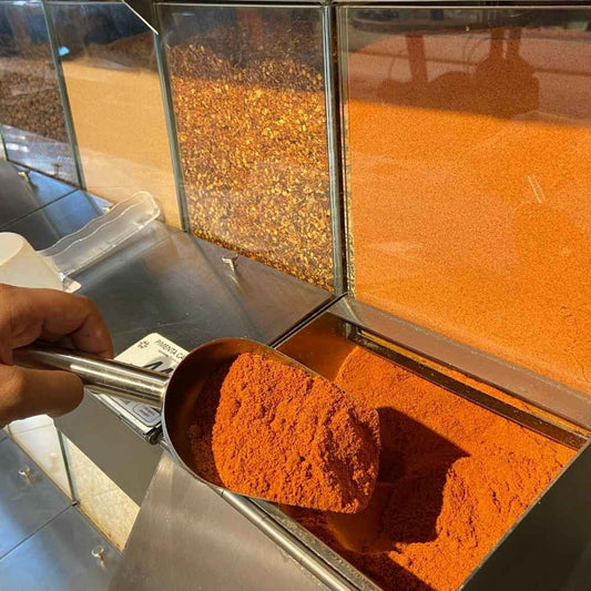 Pimenta-chilli-moida-sendo-retirada-de-um-compartimento-com-uma-pa-de-metal-destacando-sua-qualidade-e-cor-vibrante