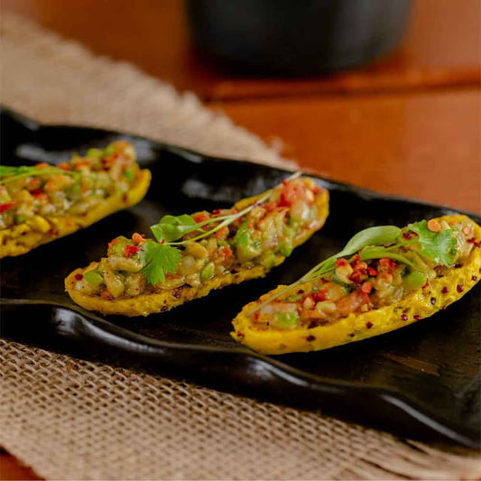 Palito-de-batata-doce-com-quinoa-e-curcuma-cortados-ao-meio-com-recheio-por-cima-em-uma-louca-preta-de-ceramica
