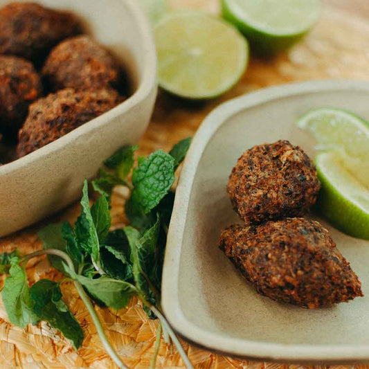 Quibe-de-carne-e-quinoa-prontos-em-dois-pratos-com-limoes-cortados-em-metades-e-um-ramo-de-hortela