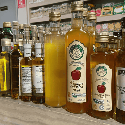 Prateleira-com-diversas-garrafas-de-vinagre-de-maca-organico-destacando-rotulos-com-certificacao-e-diferentes-tamanhos-de-embalagem